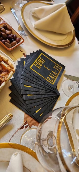 The Come E Cala-Te Cocktail Napkin (50 ct) stylish black cocktail napkins, accented with gold foil. Add a touch of Portuguese flair to your party—perfect for cocktails, tapas, or any festive gathering where friends, family, and fun come together.